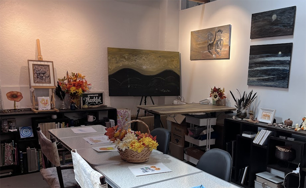 Fine art studio with oil paintings on the wall with tables down the center with sample art set out for group event.