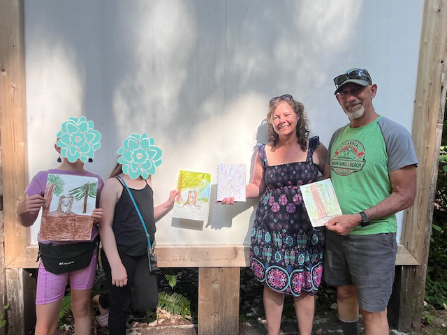 Four artists posing with their drawings at the amphitheater at the Jedediah Smith State Park.  